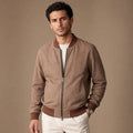 Man wearing a beige nubuck bomber jacket over a crewneck with dark denim