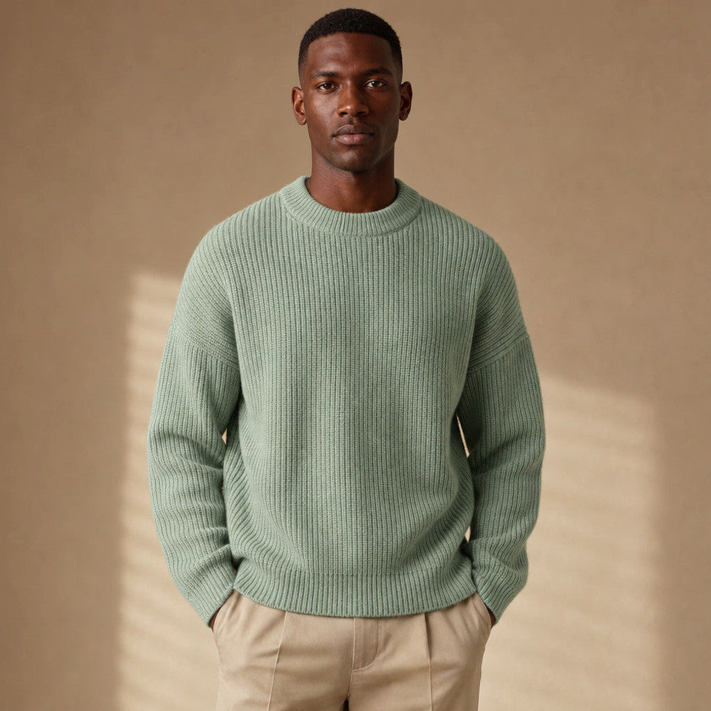 Man wearing light green ribbed drop shoulder crewneck with dark trousers