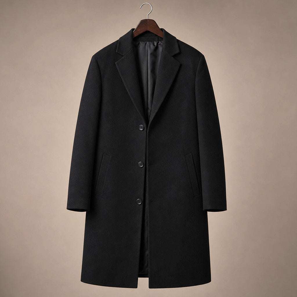 Man wearing a longline black wool overcoat buttoned over tailoring