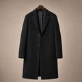 Man wearing a longline black wool overcoat buttoned over tailoring