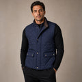 Man wearing blue quilted polo collar vest over a knit jumper