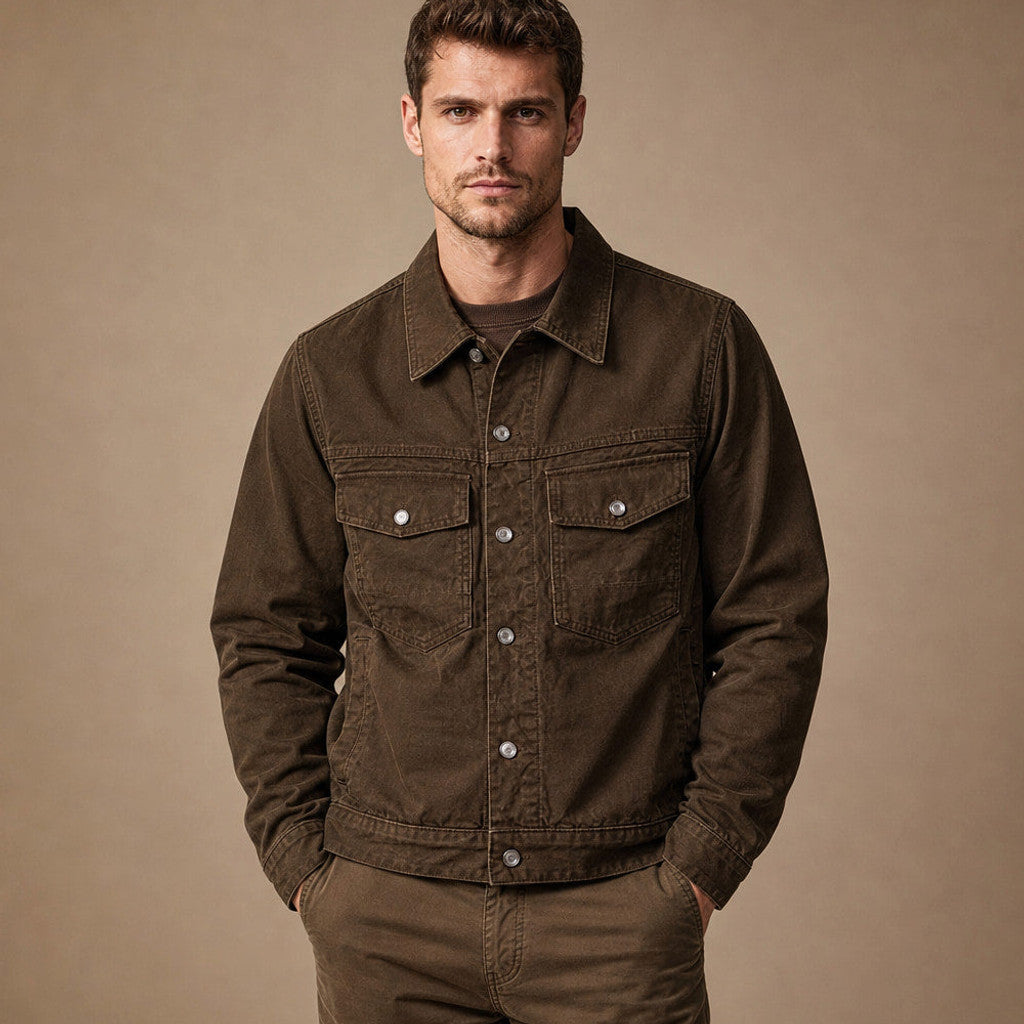 Man wearing dark brown trucker jacket over an oxford shirt and denim