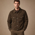 Man wearing dark brown trucker jacket over an oxford shirt and denim