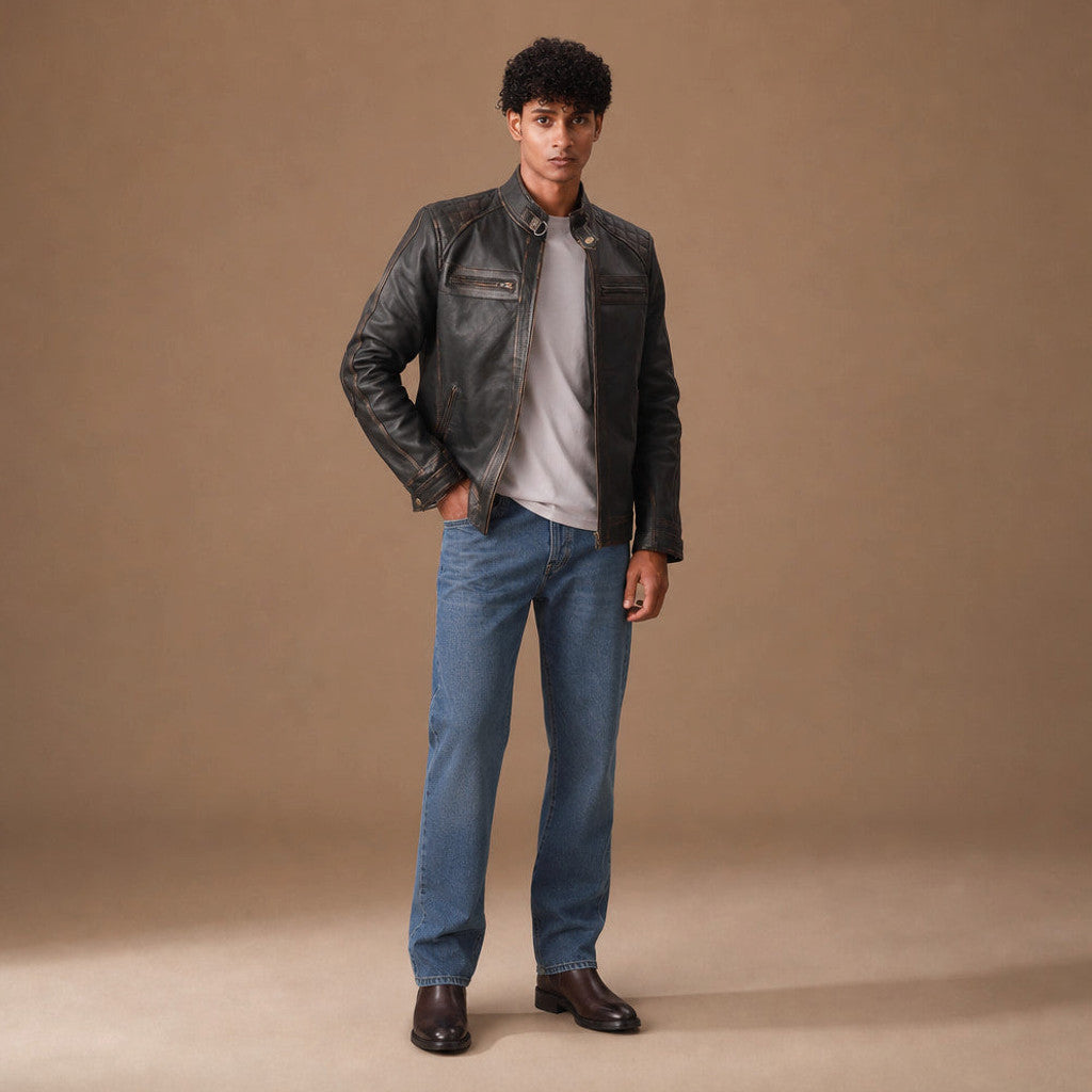Man wearing a distressed brown leather biker jacket over a knit with dark denim
