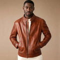 Man wearing a brown sheepskin biker jacket over a knit with dark denim