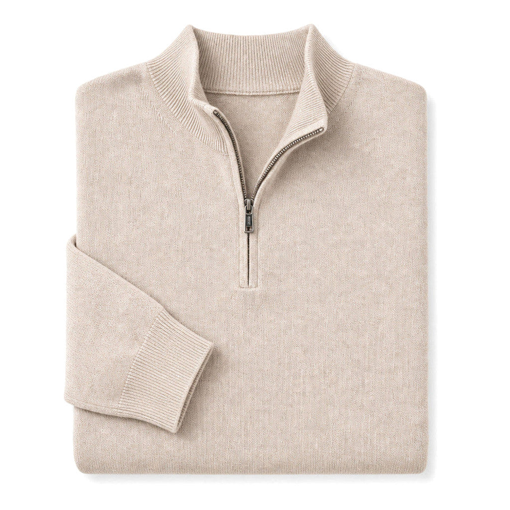 Man wearing a beige mock neck quarter zip jumper with dark trousers